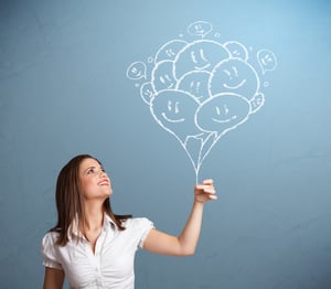 Happy young woman holding smiling balloons drawing