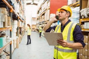 Warehouse worker talking on the phone holding clipboard in a large warehouse-2