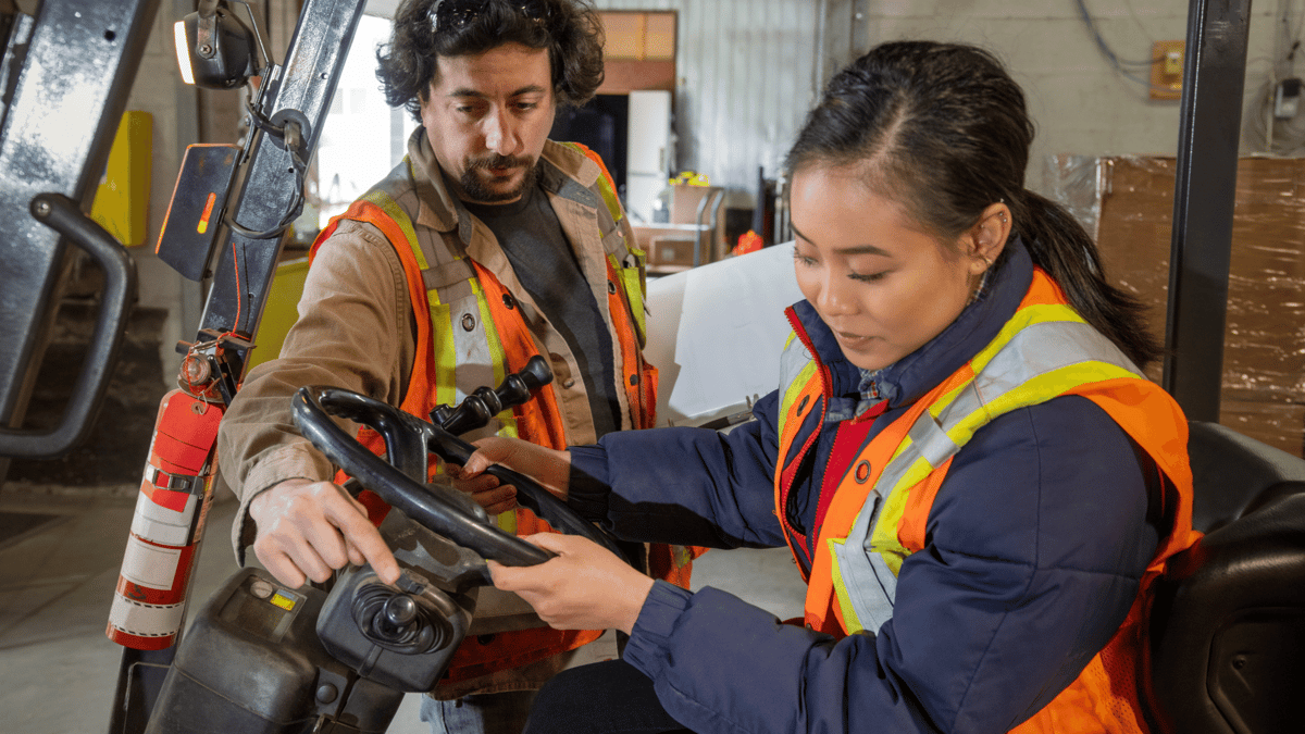 manager teaching employee how to drive forklift