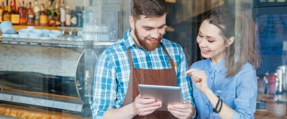 two employees looking at a message on a tablet - blog image